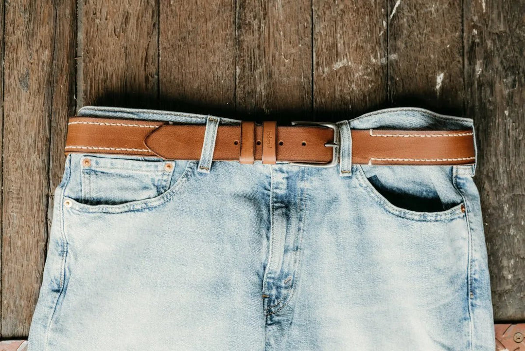 Light blue jeans with a brown leather belt on a wooden surface