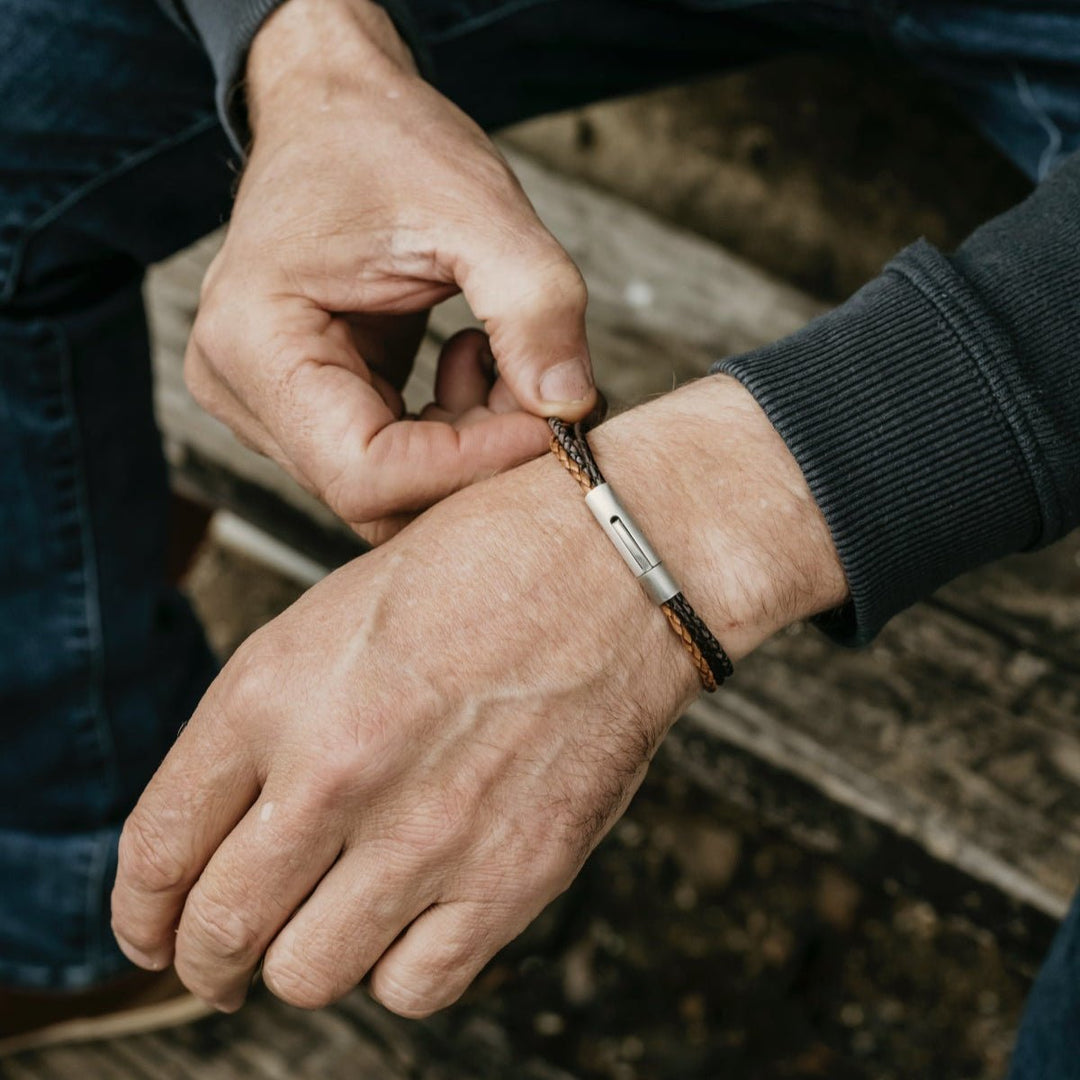 Man adjusting a leather bracelet on his wrist with a blurred background