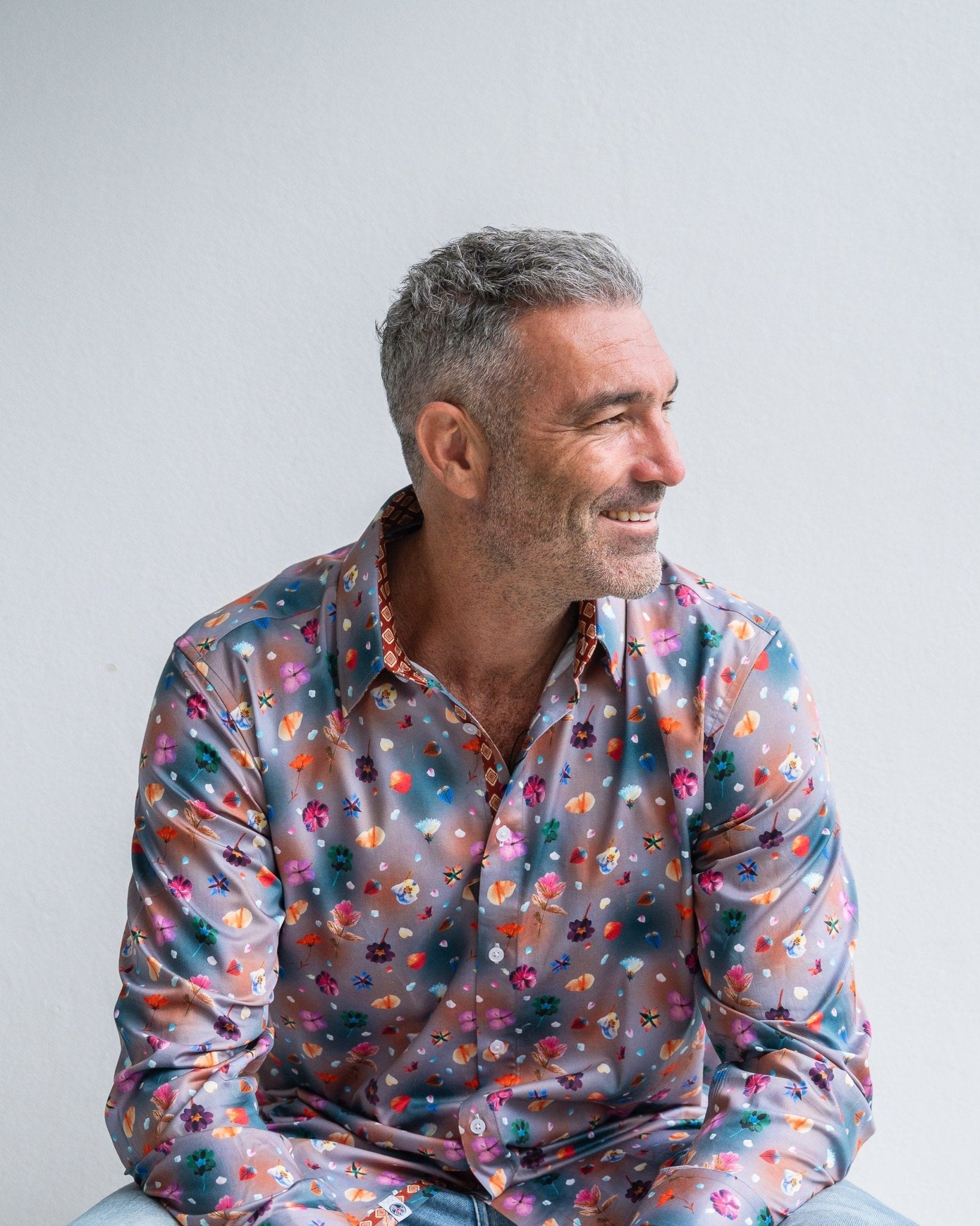 Man wearing a colorful patterned shirt against a plain background