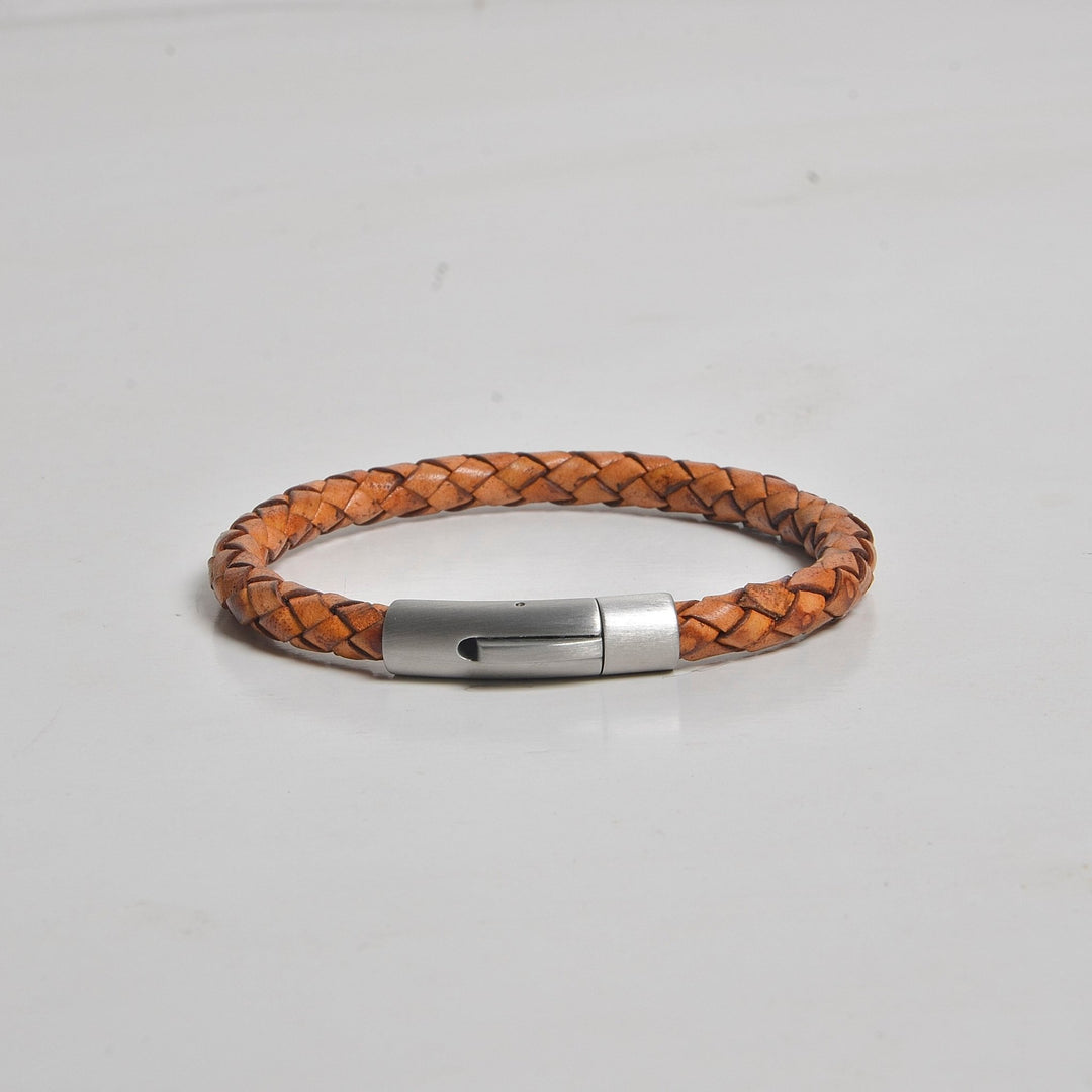 Brown braided leather bracelet with a silver clasp on a light gray background