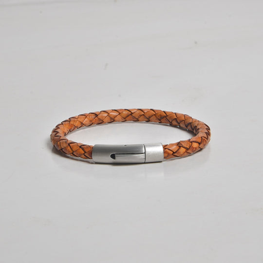 Brown braided leather bracelet with a silver clasp on a light gray background