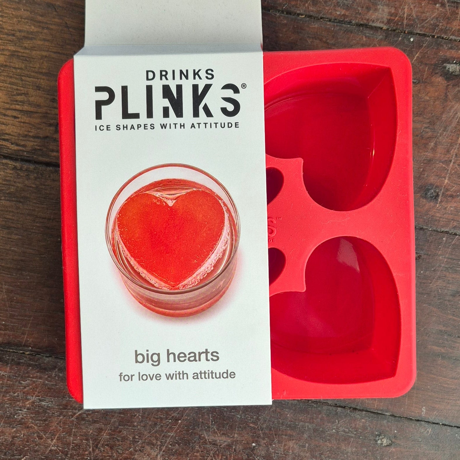 Red silicone ice tray with packaging on a wooden surface