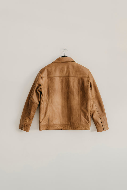 Back view of the Hailwood Raw Beige Leather Jacket by Indepal Leather from Bolt + Buckle hanging on a white wall.
