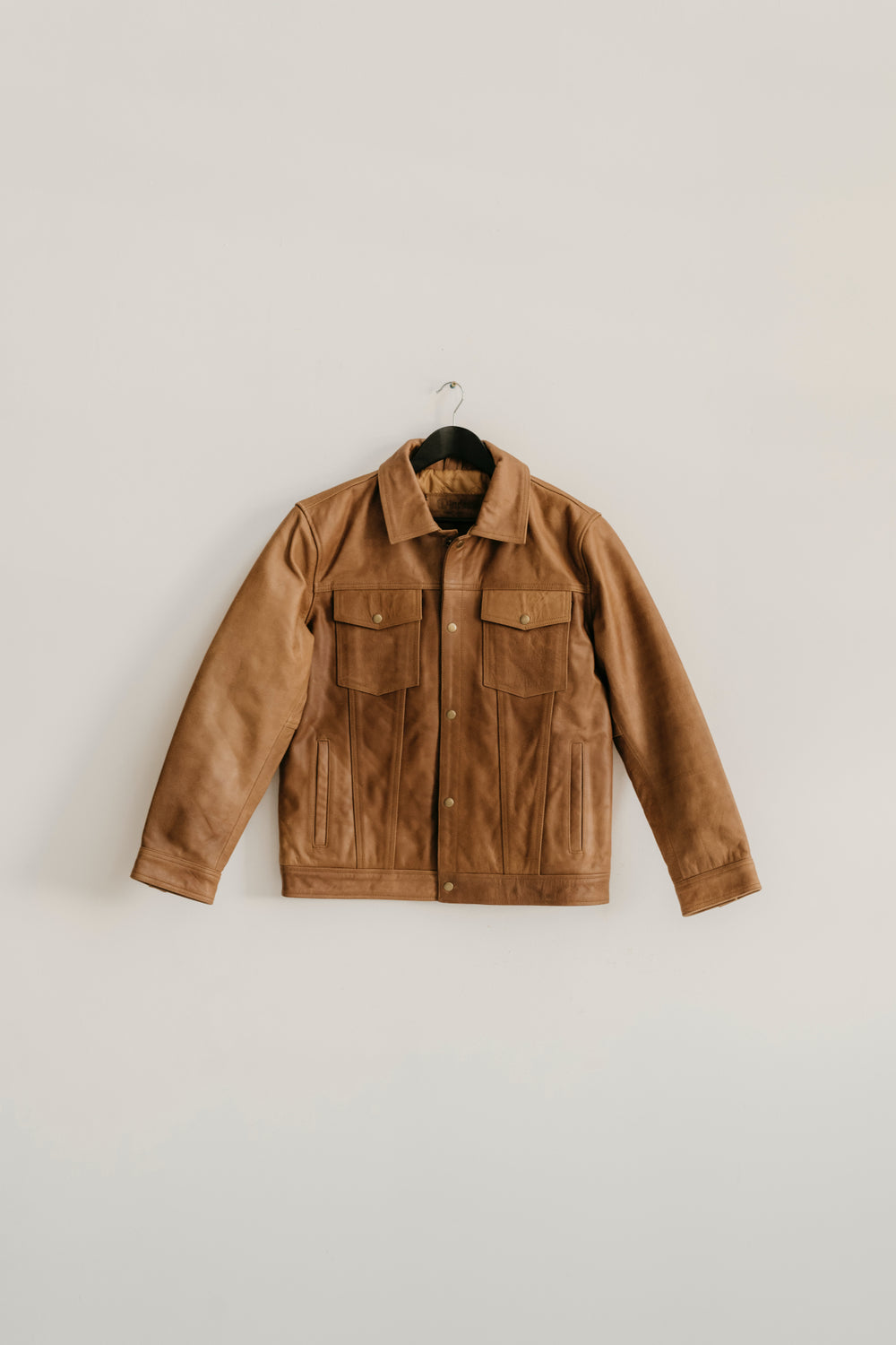 Hailwood Raw Beige Leather Jacket by Indepal Leather from Bolt + Buckle hanging on a white wall.