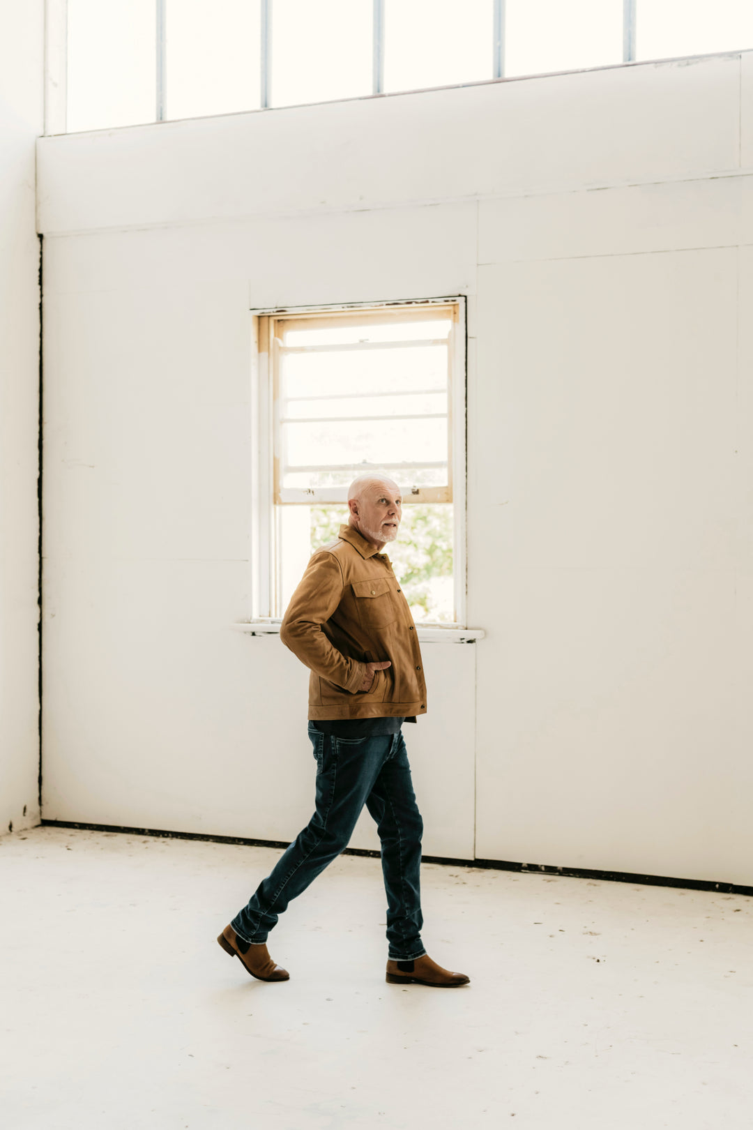 Man walking indoors wearing the Hailwood Raw Beige Leather Jacket by Indepal Leather from Bolt + Buckle, styled with jeans and brown boots.